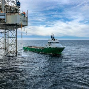 Supply vessel approaching offshore oil platform in Danish waters, showcasing maritime industry.